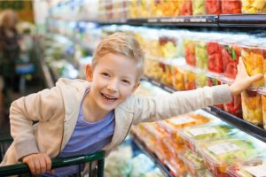 Child in Supermarket trolly reaching for pot of fruit